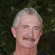 A man with white hair and mustache wearing black shirt.