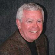 A man with white hair and wearing a suit.